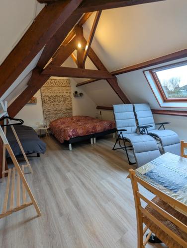 a attic room with a bed and two chairs at Le Moment Normand in Émalleville