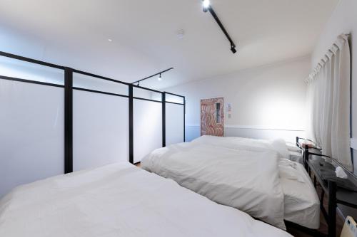 two beds in a bedroom with white sheets at Bushido Kashiwa in Kashiwa