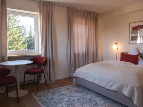 a bedroom with a bed and a table and a window at Berghotel Lindenhof in Siegsdorf