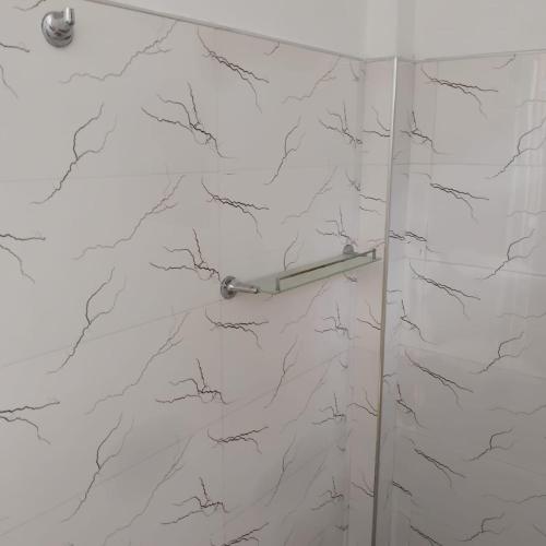 a shower with white marble walls and a glass door at Gramatic Cottage Udawalawe in Udawalawe