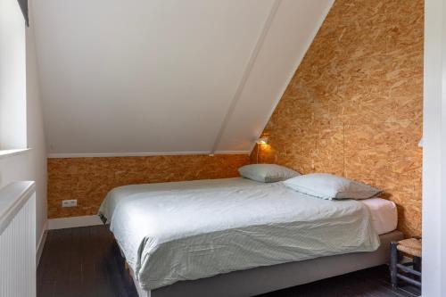 a small bedroom with a bed with white sheets at Guesthouse de Bovenboer in Nijeveen
