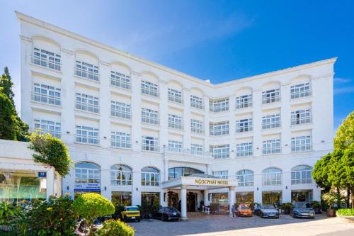 un grande edificio bianco con le auto parcheggiate di fronte di Ngoc Phat Dalat Hotel a Da Lat