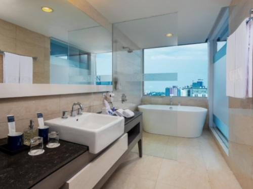 a bathroom with a sink and a bath tub and a tubermott at Aston Makassar Hotel & Convention Center in Makassar