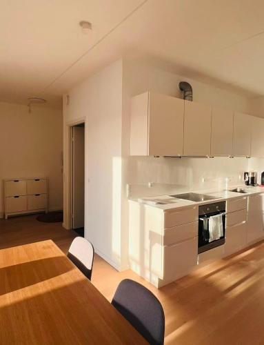 a kitchen with white cabinets and a table and chairs at Ama Hyg Atelier Copenhagen Royal Arena 2 Bedrooms Apartment in Copenhagen
