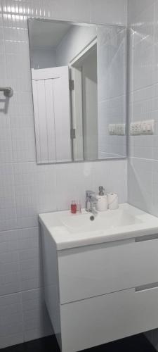 a white bathroom with a sink and a mirror at Arisara place in Koh Samui