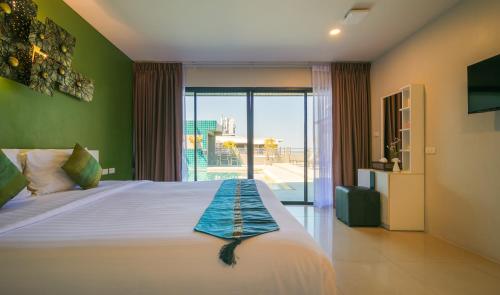 a bedroom with a bed and a large window at Gu Hotel Patong in Patong Beach