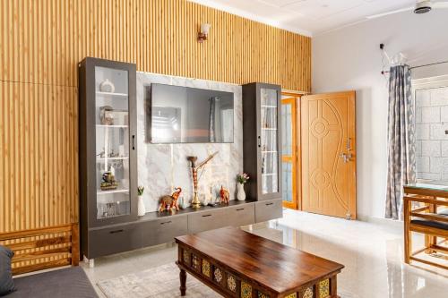 a living room with a table and a large entertainment center at Baidehi Cottage in Rishīkesh