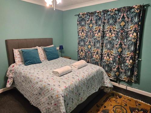 a bedroom with a bed with a blanket and a curtain at Moredon Bungalow in Swindon