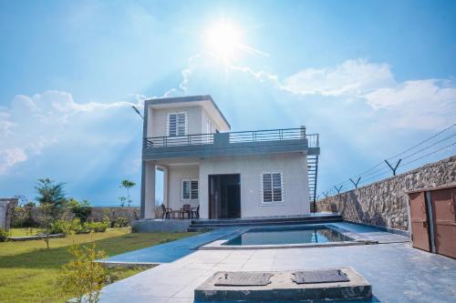 a villa with a swimming pool in front of a house at Silverleaf Homestay in Borāj