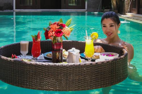 een vrouw in een zwembad met een tafel vol eten bij Mahagiri Villas Sanur in Sanur