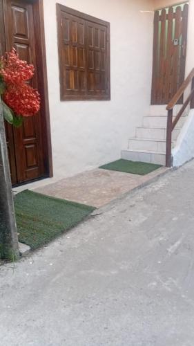 a building with a door and stairs with red flowers at Casa do Carlos Boipeba 2 in Cairu
