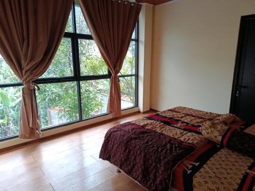 a bedroom with large windows and a bed in it at Selaras Heritage Villa in Campaka