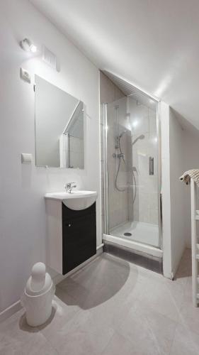a white bathroom with a shower and a sink at Studio Foch 4 in Grand-Fort-Philippe