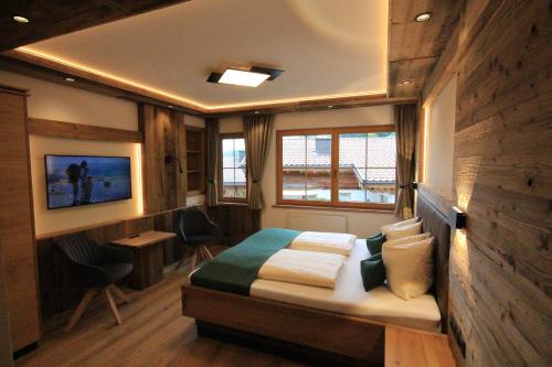 a bedroom with a bed and a desk and a window at Haus Dorfblick in Gerlos