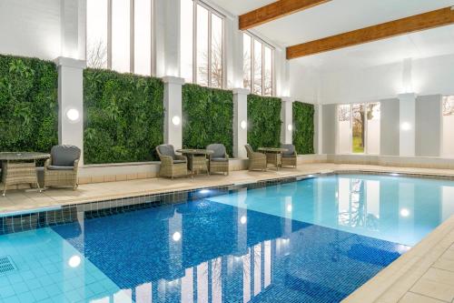 a pool with chairs and tables in a building at Daresbury Park Hotel in Daresbury