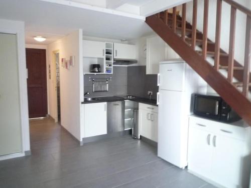 a kitchen with white cabinets and a staircase at La casa du creux in Valras-Plage