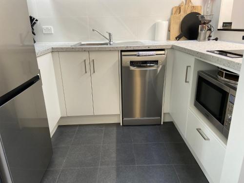 a kitchen with white cabinets and a stainless steel dishwasher at Foreshore Apartment 104 in Albany