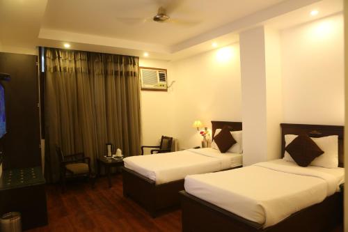 a hotel room with two beds and a table at Hotel Kamla Palace in Dehradun