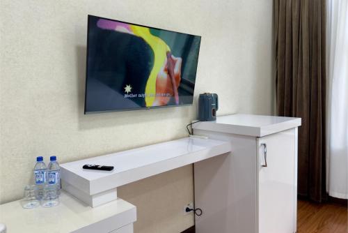 a bathroom with a white sink and a tv on the wall at Wellmore Resort in Yusufkhona