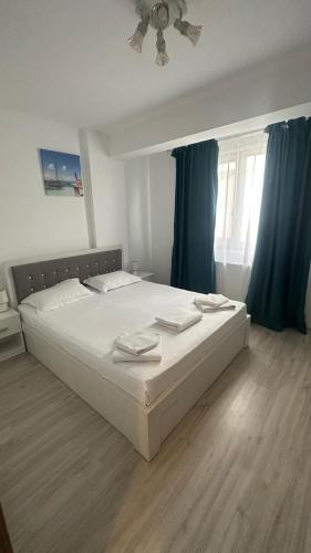 a bedroom with a large bed with blue curtains at La Playa Residence in Năvodari