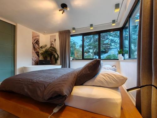 a bedroom with a large bed with a large window at Huize Triangel - Wellness studio met sauna in Noordwolde