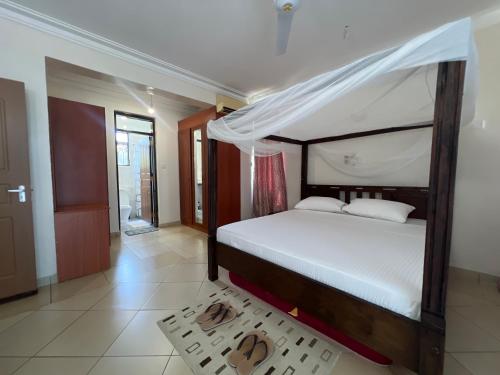 a bedroom with a bed with a canopy at Ary Homestay Nyali At Shikara Apartments 5th Avenue Nyali, Mombasa, Kenya in Mombasa