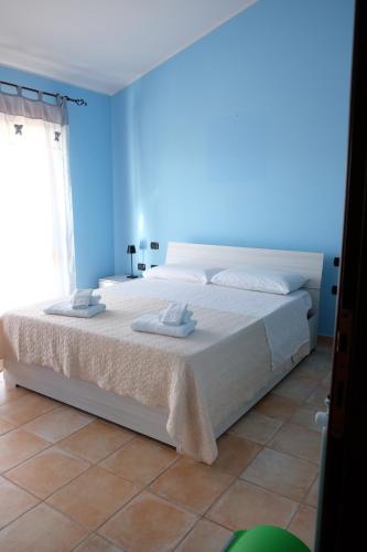 a bedroom with a large white bed with a blue wall at B&B Sa Sinniesa in Sìnnai