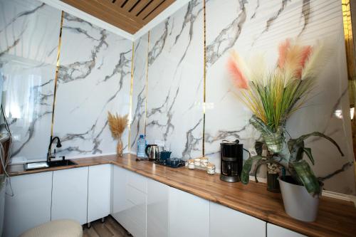 a kitchen with white cabinets and a marble wall at Asem Hotel in Nukus