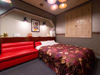 a bedroom with a red bed and a red couch at ホテルツクバランド in Tōgane
