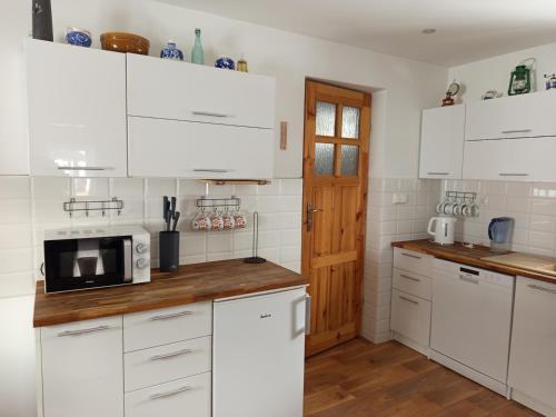 een keuken met witte kasten en een magnetron bij Stare Sioło in Wysokie