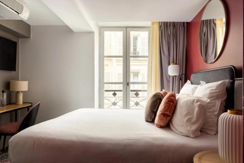 une chambre avec un grand lit blanc et une fenêtre dans l'établissement La Dépendance, à Paris