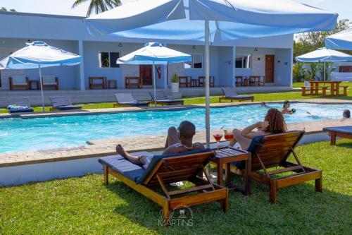 a man and woman sitting in chairs by a pool at Villa Martins, Inhaca, Mozambique in Portinho da Inhaca