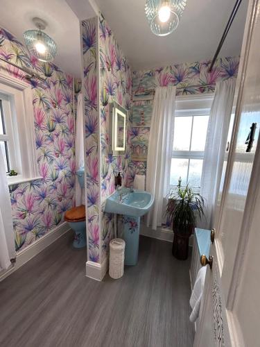 a bathroom with a sink and a flowery wallpaper at Greylands Guest House in Llandrindod Wells