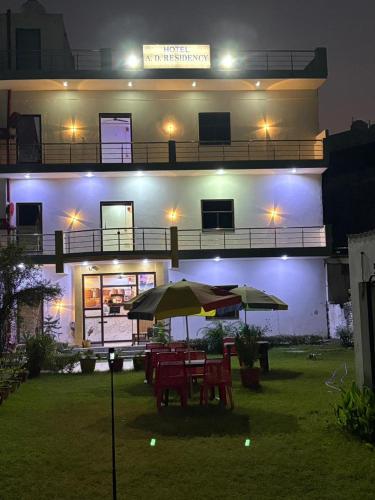 a building with tables and umbrellas in a yard at night at AD ressidency Hotel in Agra