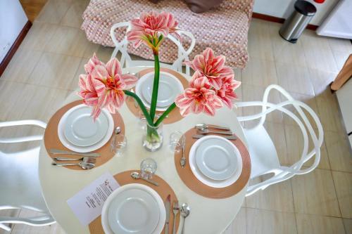 a table with plates and flowers on top of it at Villa Capri first floor in Quatre Bornes