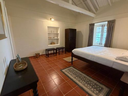a bedroom with a bed and a table and a window at Ellem House in Kotagiri