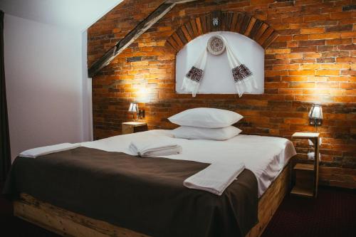 a bed in a room with a brick wall at Hanul Teilor in Dăneşti