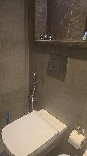 a bathroom with a white toilet and a mirror at Lake Side Drift by Luxury loft 37th floor in Noida