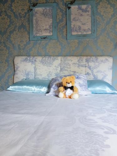 a teddy bear sitting on top of a bed at La Petite France in Nova Petrópolis