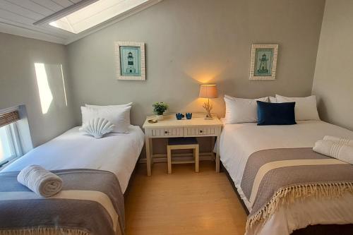 two beds in a room with a desk between them at 85 The Dunes in Keurboomstrand