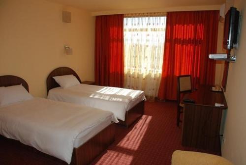 Habitación de hotel con 2 camas y TV en Hotel Coliseum, en Calafat