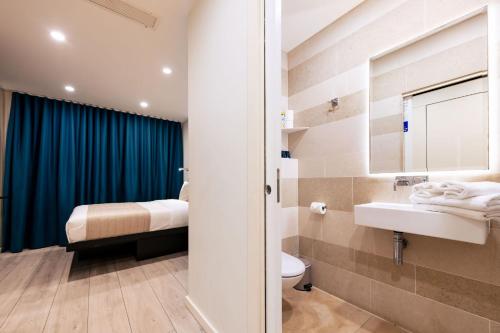 a bathroom with a toilet and a sink and a bed at NOX Golders Green in London