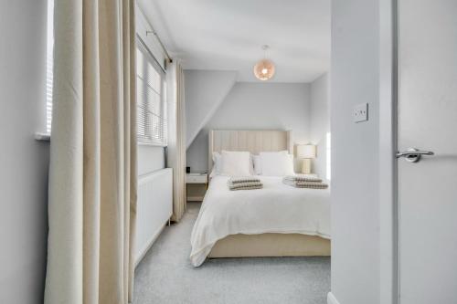a white bedroom with a bed and a window at Lovely 2-Bed House with parking in Broomfield