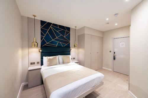 a bedroom with a large bed with a blue headboard at NOX Golders Green in London