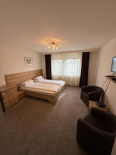 a bedroom with a bed and two chairs in it at K&I Panzió in Comolău