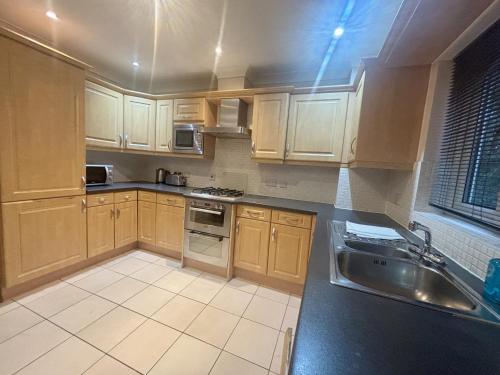 a kitchen with wooden cabinets and a sink at Bracknell Spacious Two Bedroom Apartment in Bracknell