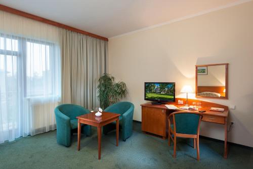 a hotel room with a desk and chairs and a television at April hotel Panorama in Rychnov nad Kněžnou