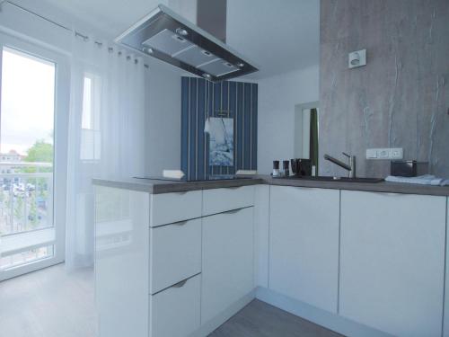 a kitchen with white cabinets and a sink and a window at Kirchenplatz 6 Apartment 17 in Warnemünde