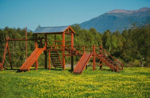 een houten speeltuin in een bloemenveld bij Cabañas Puerto Aysen in Puerto Aisén