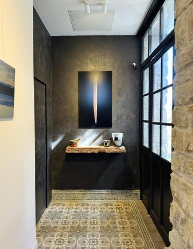 a hallway with a black wall with a shelf and a window at Maison Bruno Di Salvio in Les Vans